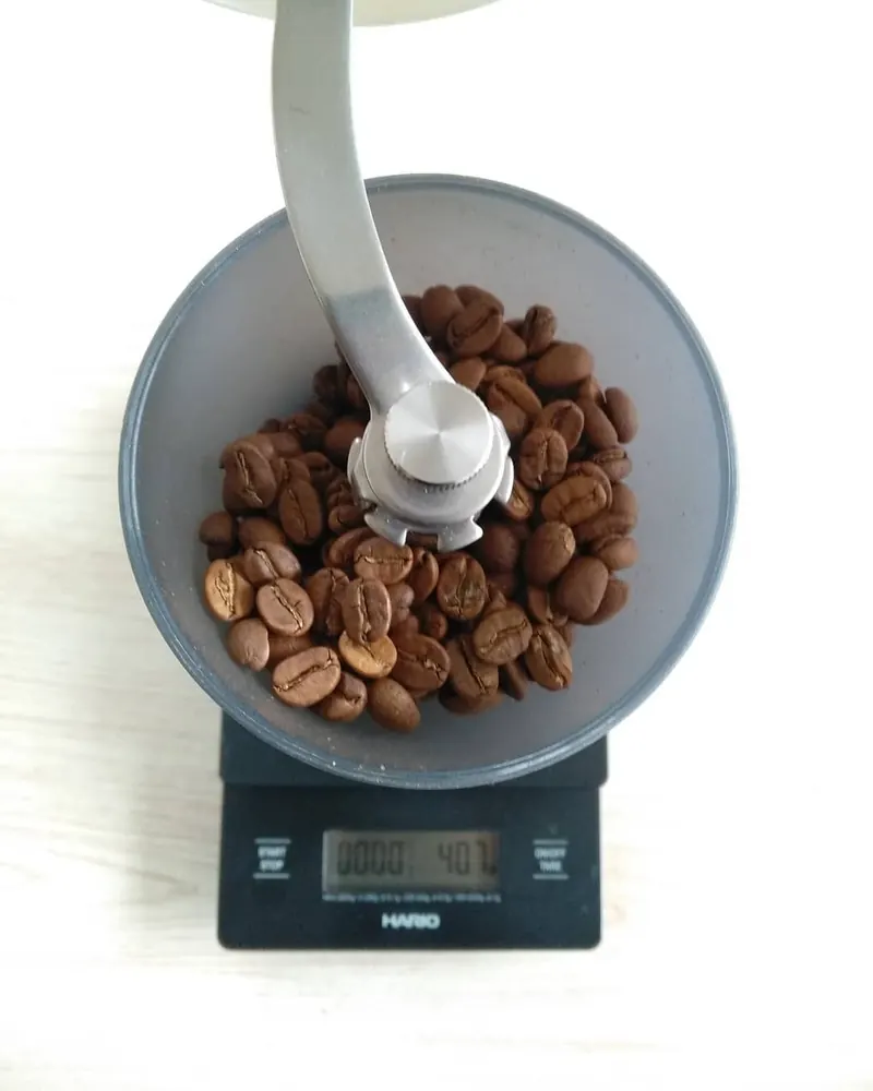 Molino manual con granos de café sobre una báscula